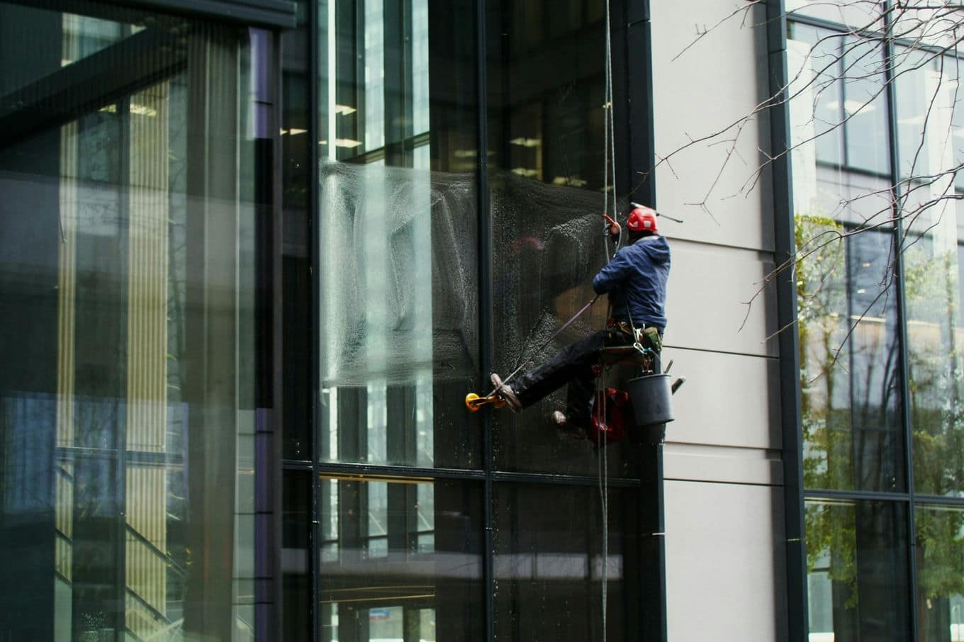 alpinista myjący okna w budynku